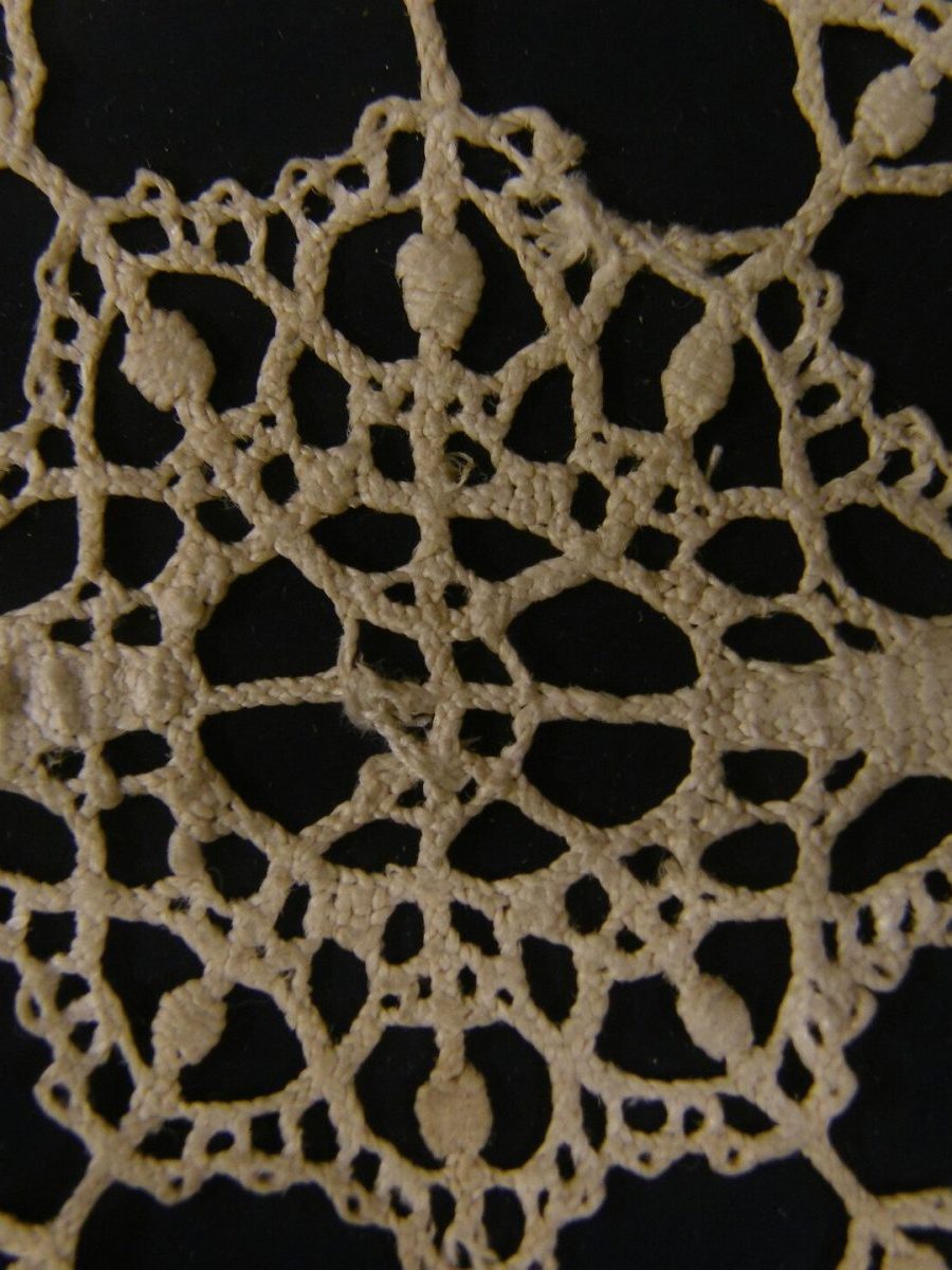Hand-worked bobbin lace photographed against black
