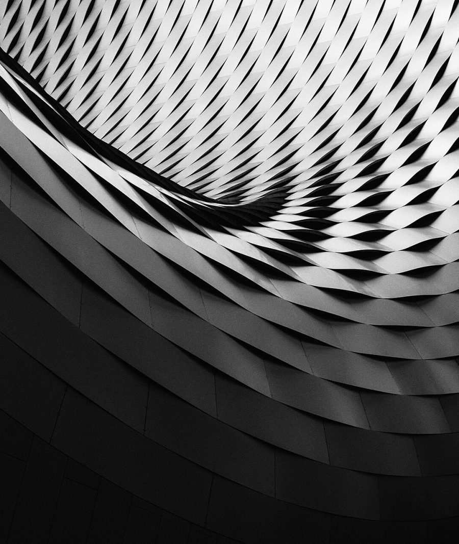 Monochrome spiral of pleated forms receding into shadow